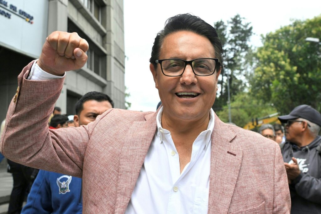 A person in a suit with his fist up

Description automatically generated