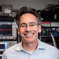 A person wearing glasses smiling
Description automatically generated