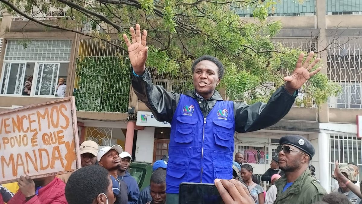 A person in a blue vest with his hand up

Description automatically generated
