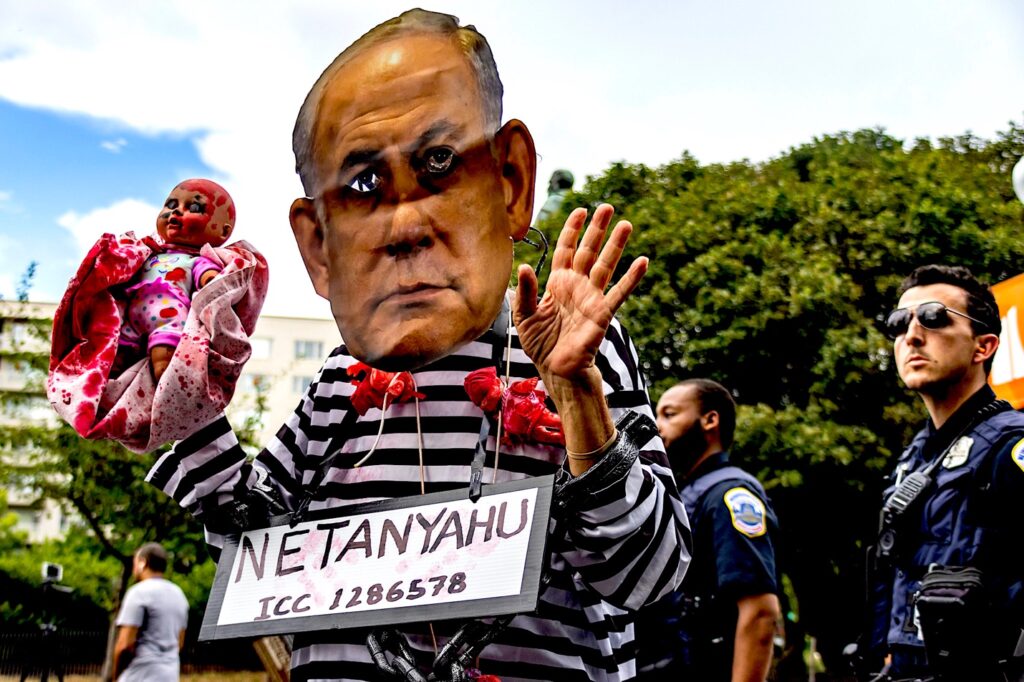 A person in a striped shirt holding a sign Description automatically generated