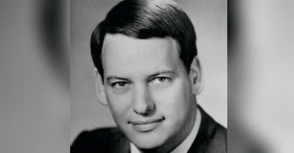 A person in a suit smiling

Description automatically generated