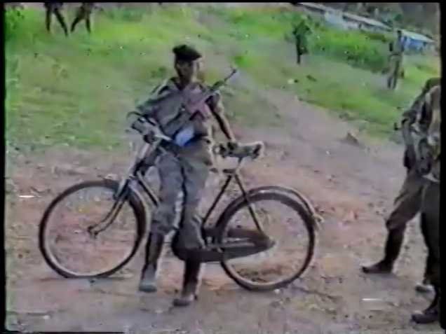 A person sitting on a bicycle next to a bear<br><br>Description automatically generated