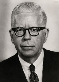 A person wearing glasses and a suit

Description automatically generated