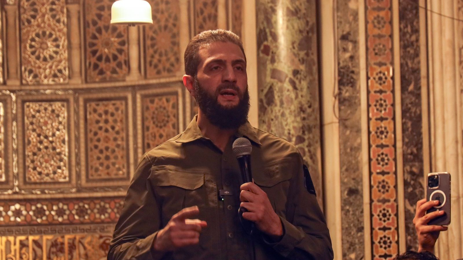 A person with a beard speaking into a microphone

AI-generated content may be incorrect.
