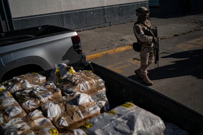 A soldier standing in front of a truck full of bags

AI-generated content may be incorrect.