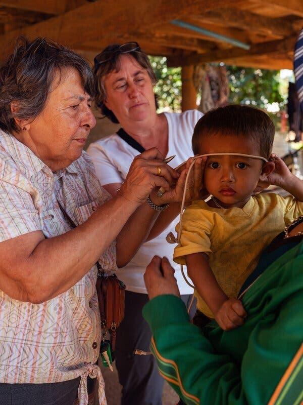 A group of people measuring a child's head

Description automatically generated