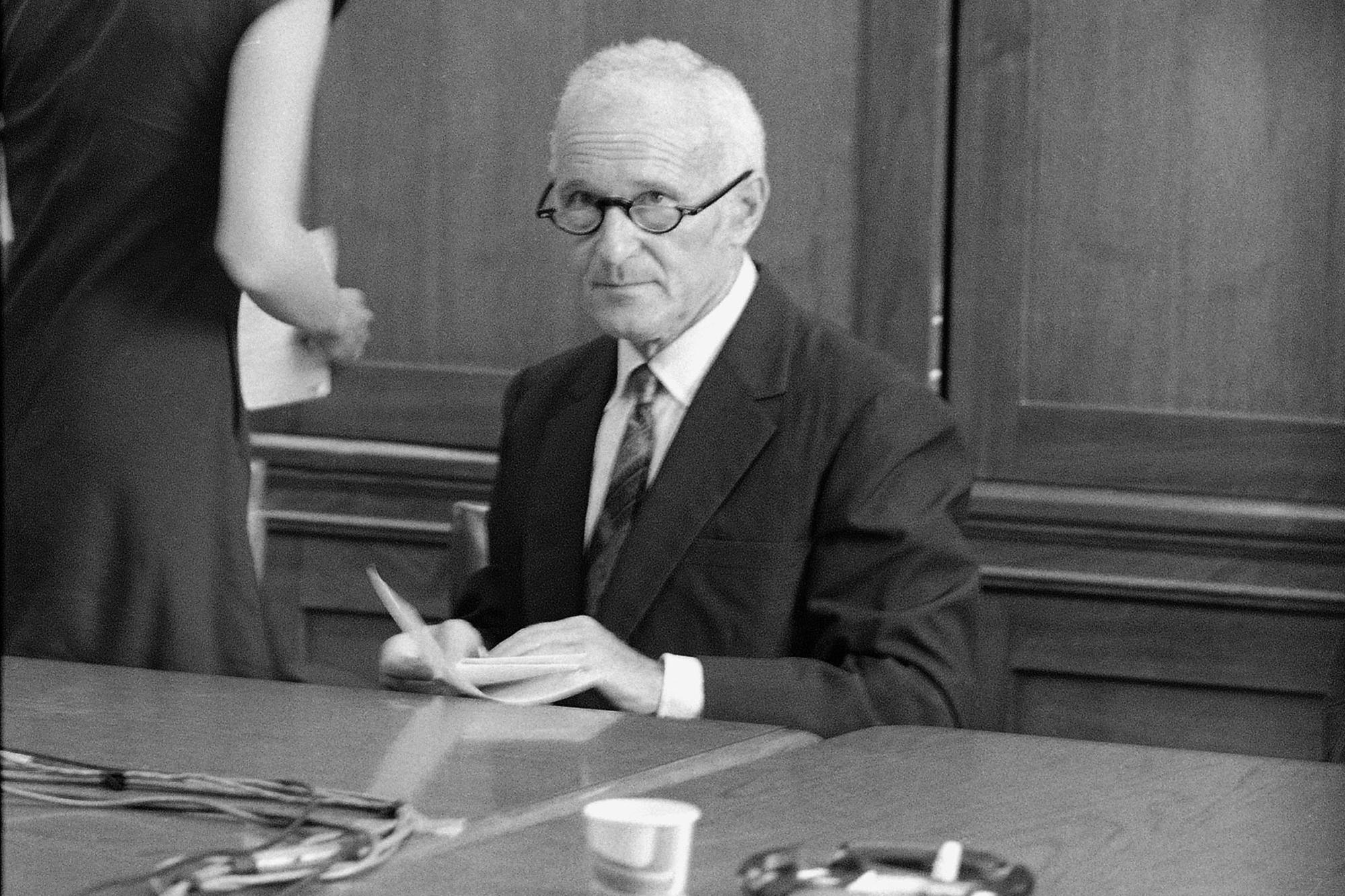 A person in a suit and tie sitting at a table
AI-generated content may be incorrect.