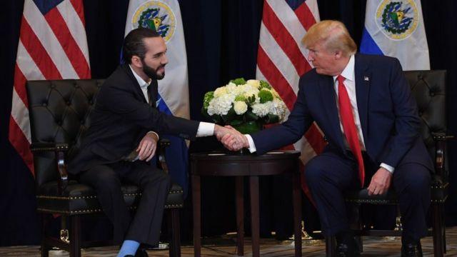 Two men shaking hands in front of flags

AI-generated content may be incorrect.