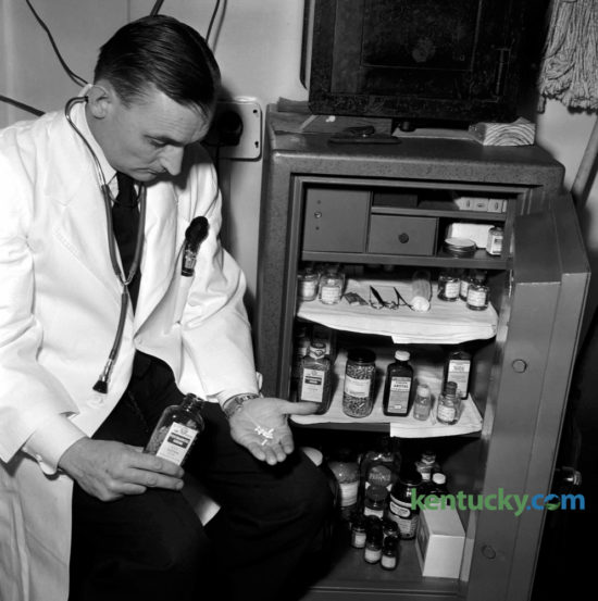 A doctor looking at a small safe
Description automatically generated