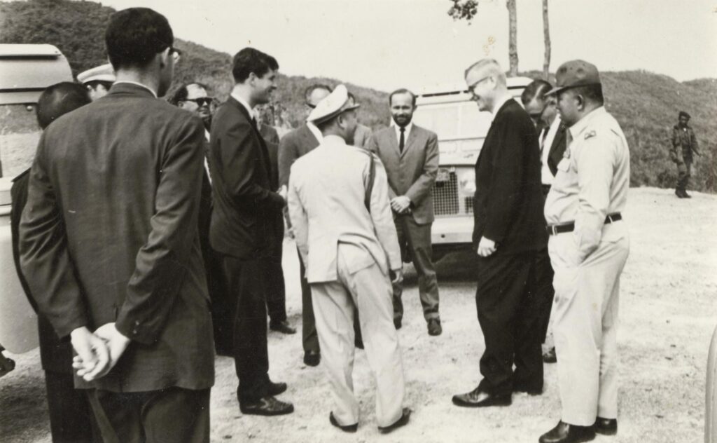 A group of men standing around each other Description automatically generated
