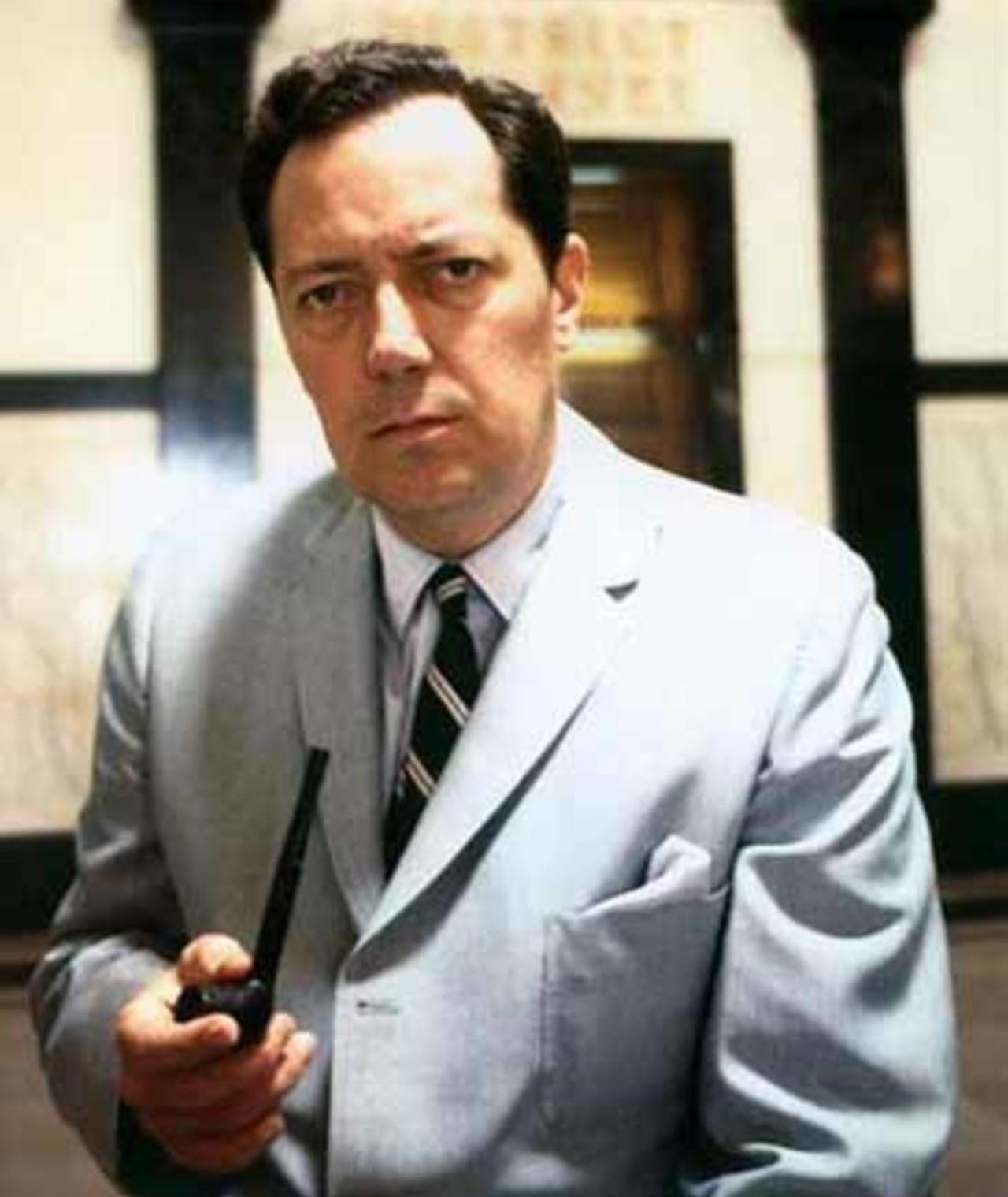 A person in a suit holding a radio

Description automatically generated