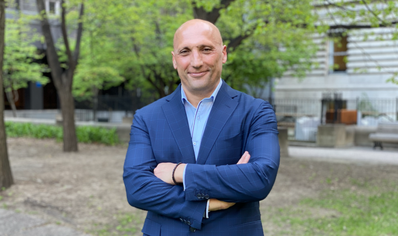 A person in a suit with his arms crossed
AI-generated content may be incorrect.