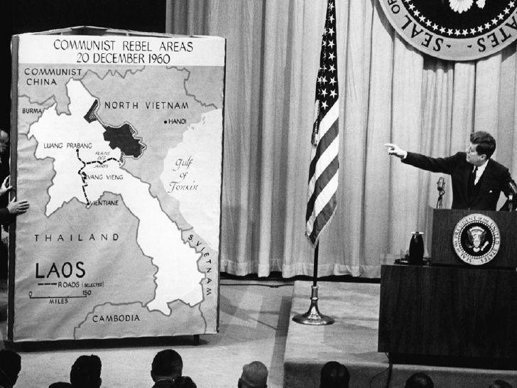 A person standing at a podium with a flag and a flag
Description automatically generated