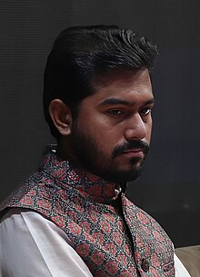 A person with a beard and mustache wearing a vest

AI-generated content may be incorrect.