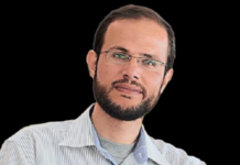 Giving Voice to Gazans Targeted by the U.S.-Israeli Death Machine A person with glasses and a beard Description automatically generated