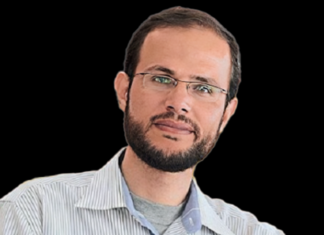 Giving Voice to Gazans Targeted by the U.S.-Israeli Death Machine A person with glasses and a beard Description automatically generated