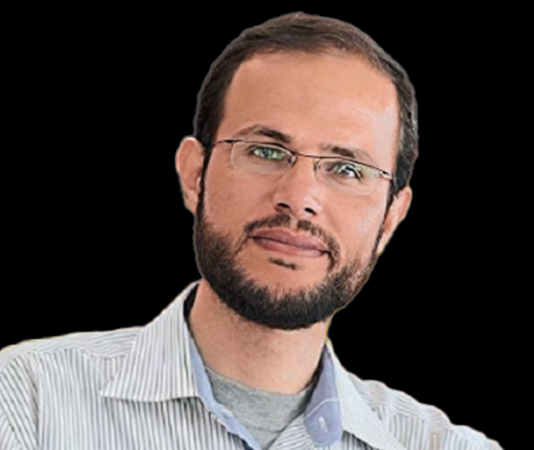 Giving Voice to Gazans Targeted by the U.S.-Israeli Death Machine A person with glasses and a beard Description automatically generated