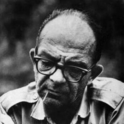 A person with glasses and a cigarette in his mouth
Description automatically generated