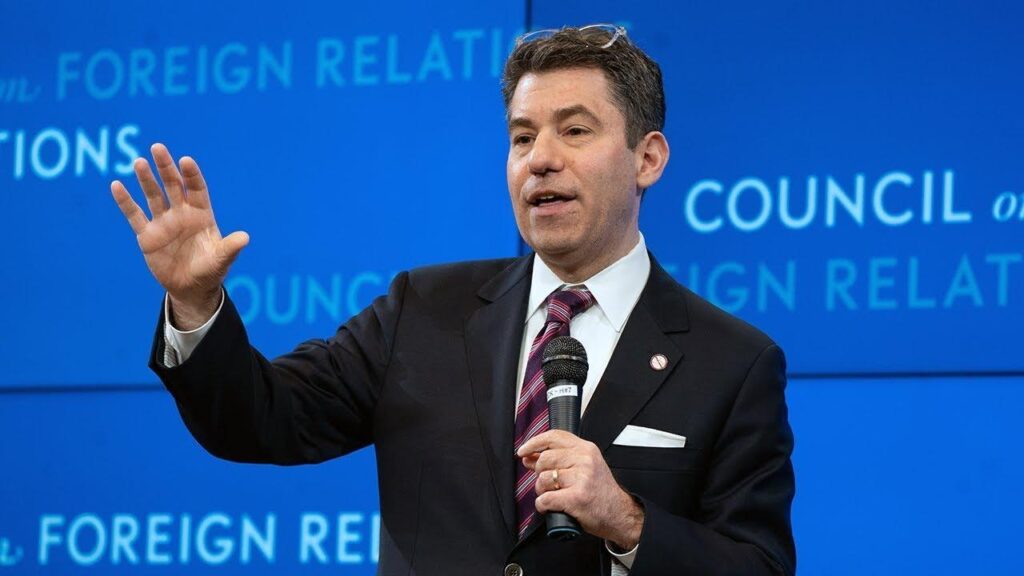 A person in a suit holding a microphone

AI-generated content may be incorrect.