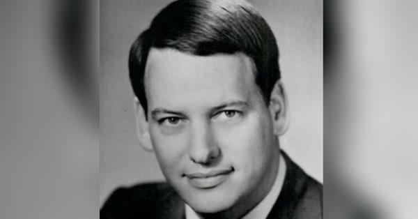 A person in a suit smiling
Description automatically generated