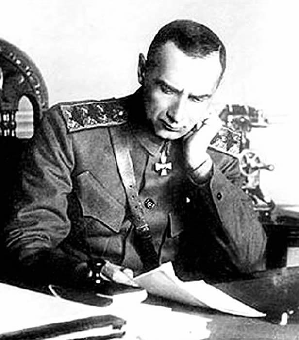 A person in military uniform sitting at a desk

Description automatically generated