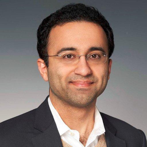 A person wearing glasses and a suit

Description automatically generated