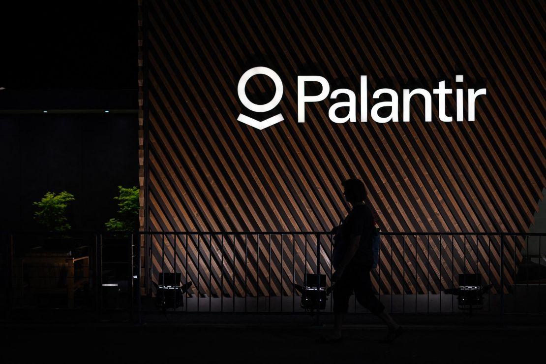 A woman walks under a sign of big data analytics US software company Palantir in Davos on May 22, 2022.