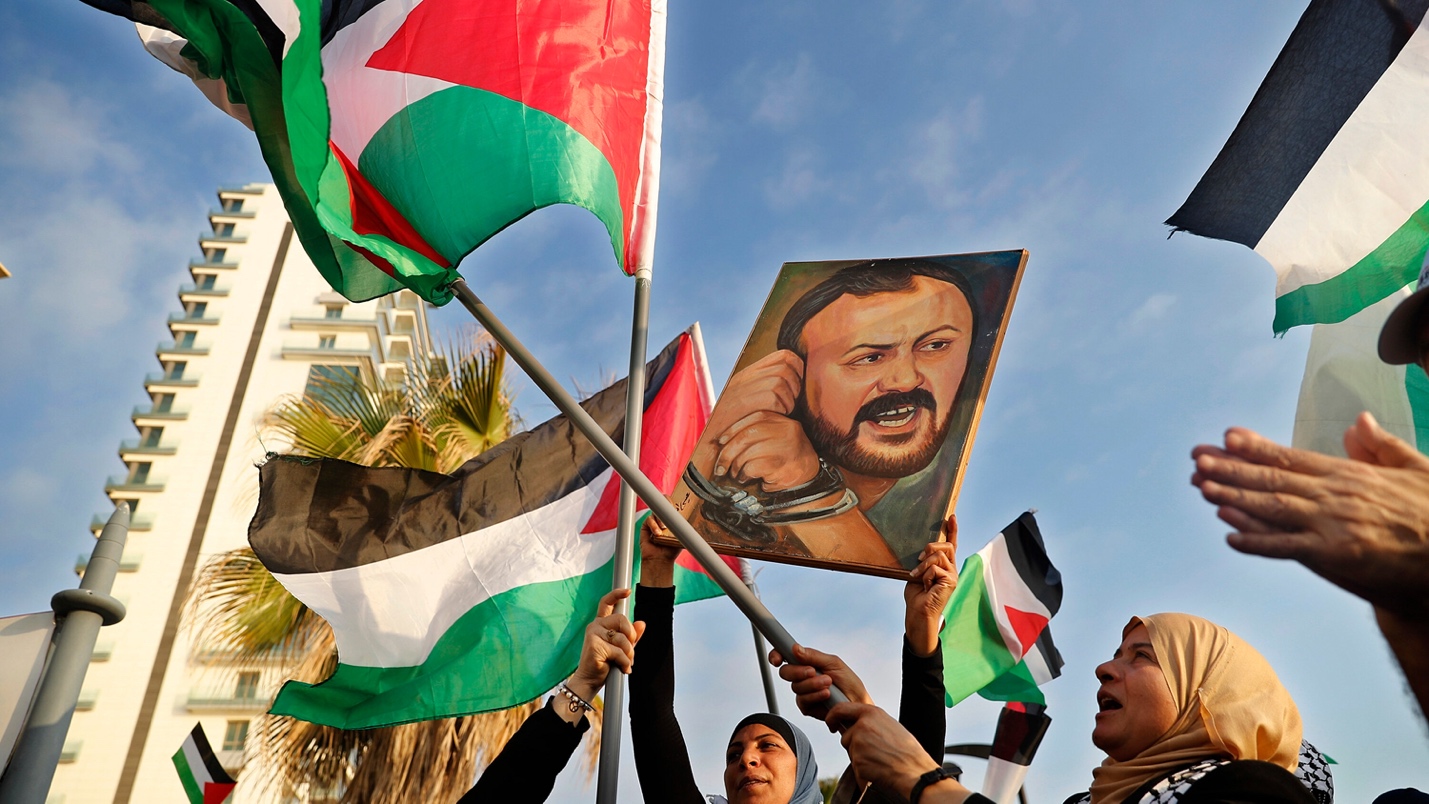 A group of people holding flags and a portrait of a person

AI-generated content may be incorrect.