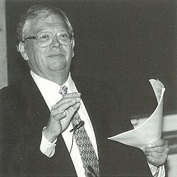 A person in a suit holding a paper
AI-generated content may be incorrect.