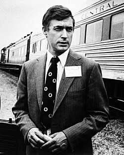 A person in a suit standing next to a train

AI-generated content may be incorrect.