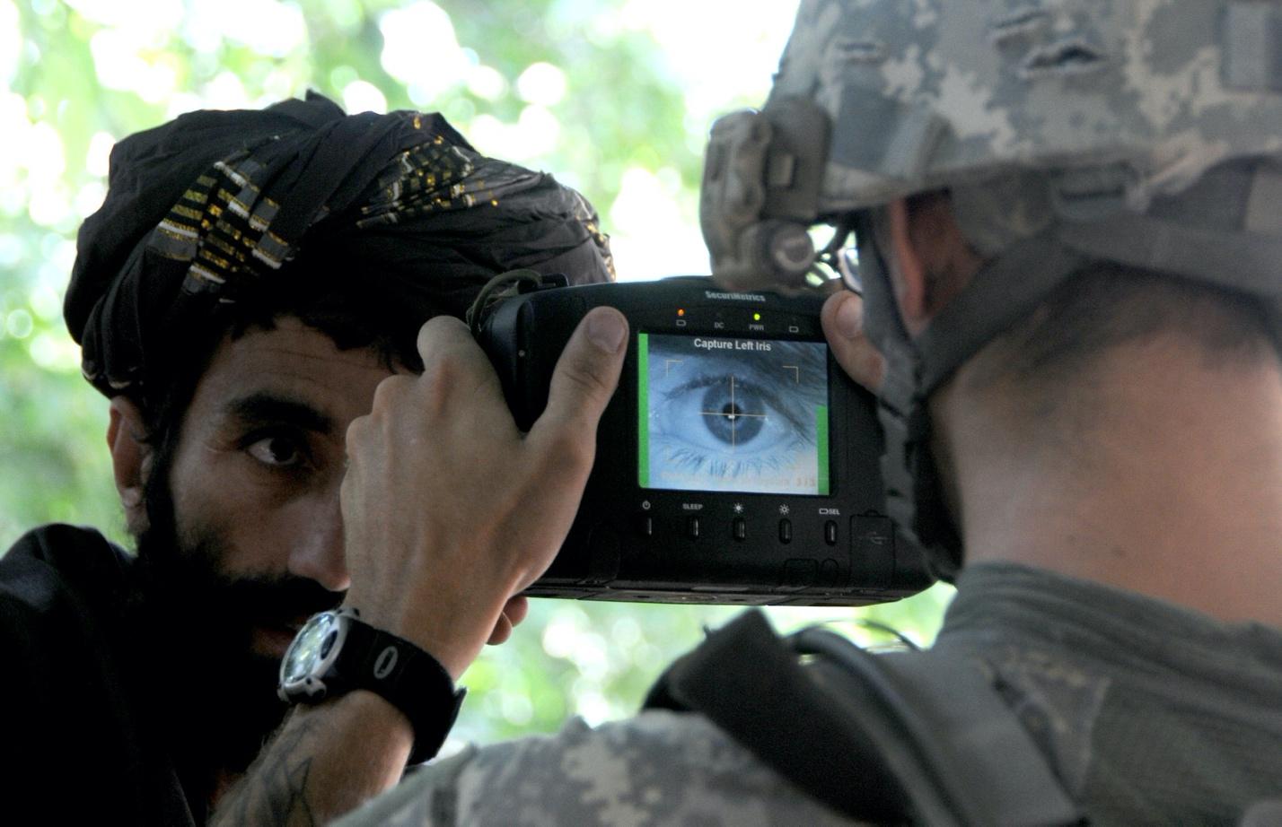 A soldier taking a picture of a person
Description automatically generated