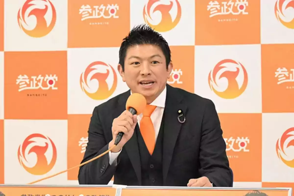 A person in a suit and tie speaking into a microphone
AI-generated content may be incorrect.