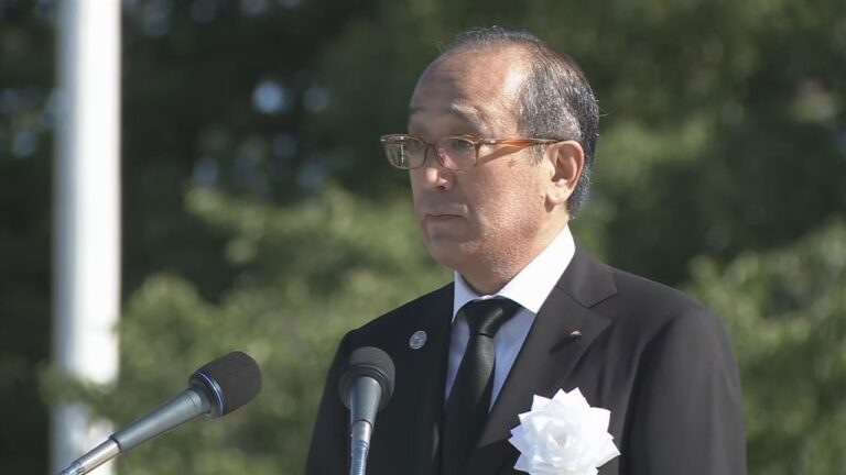 A person in a suit and tie standing in front of microphones

AI-generated content may be incorrect.