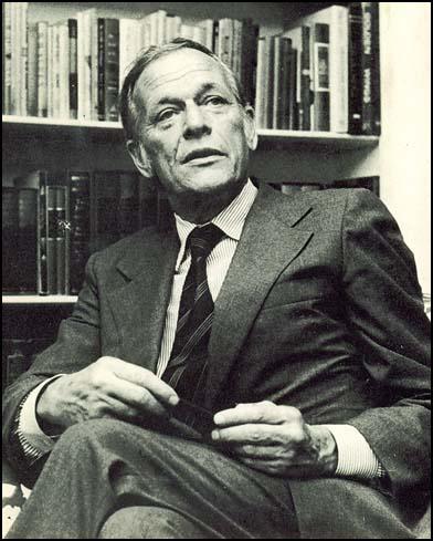 A person in a suit sitting in front of a bookshelf
AI-generated content may be incorrect.