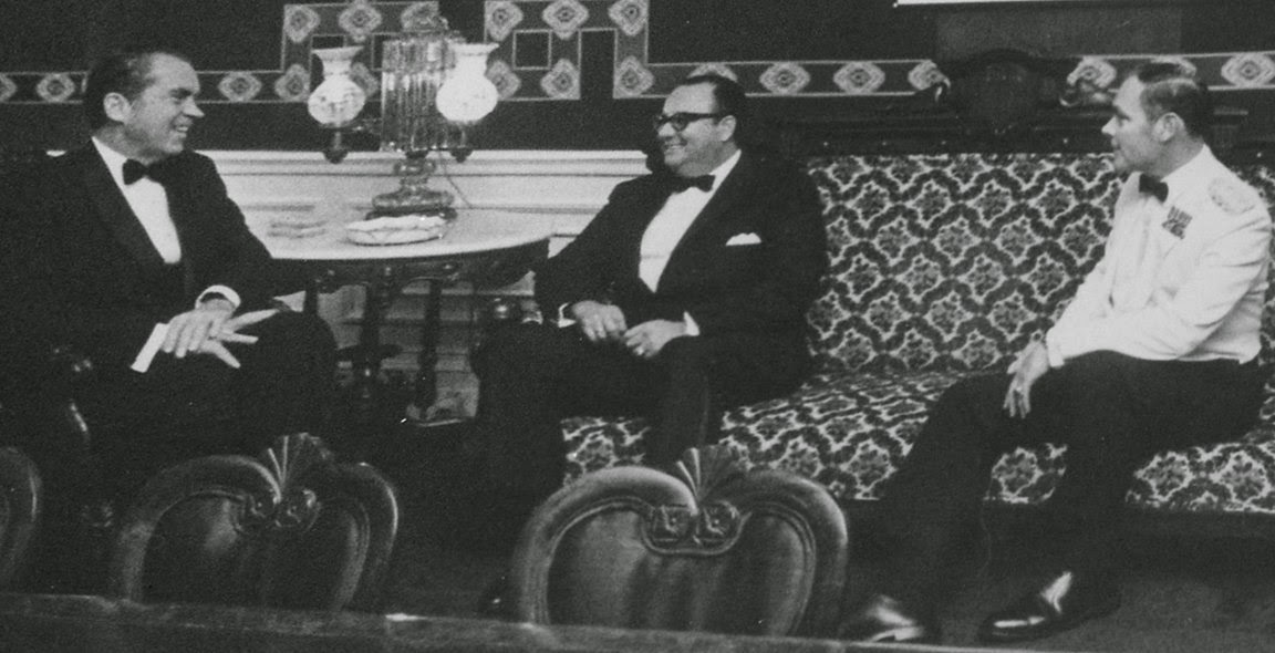A person in a suit sitting on a couch
AI-generated content may be incorrect.