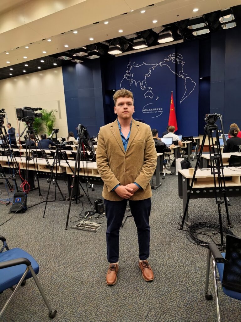 A person standing in a room with microphones and a map

AI-generated content may be incorrect.