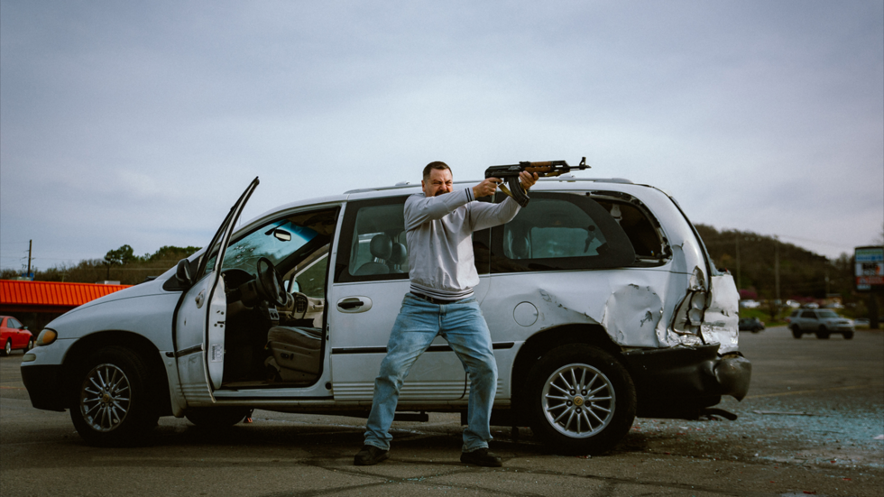 A person holding an object in front of a van
AI-generated content may be incorrect.