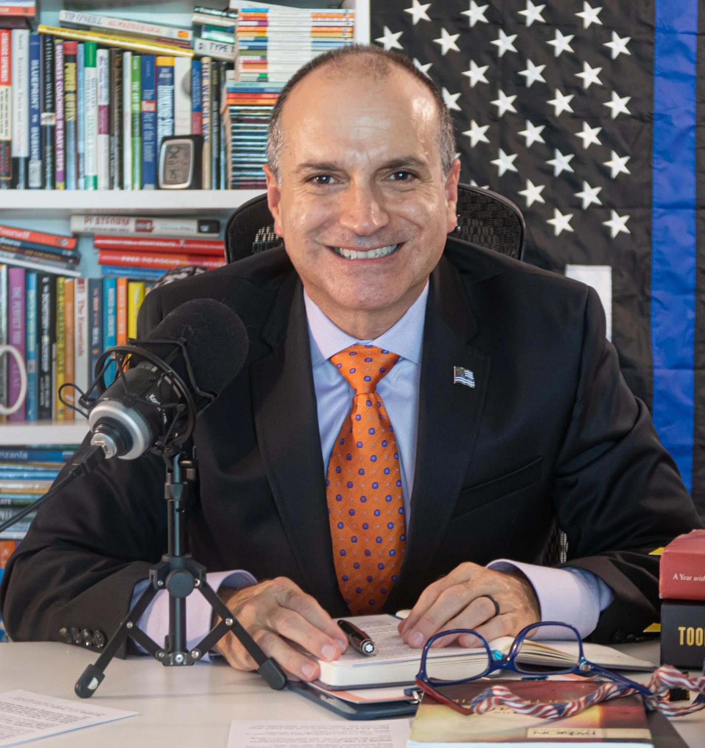 A person sitting at a desk with a microphone and a book

AI-generated content may be incorrect.