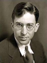 A person wearing glasses and a suit
Description automatically generated