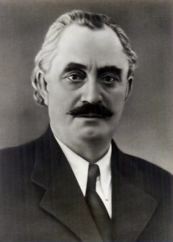 A person with a mustache wearing a suit and tie
AI-generated content may be incorrect.
