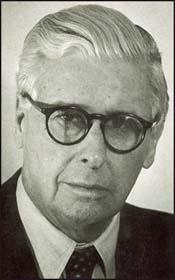 A person wearing glasses and a suit

Description automatically generated