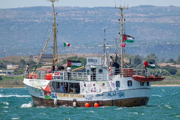 A ship covered in graffiti and carrying Palestinian flags at sea.