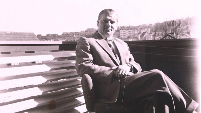 A person in a suit sitting on a chair

AI-generated content may be incorrect.