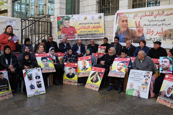 People hold placards with faces of people.