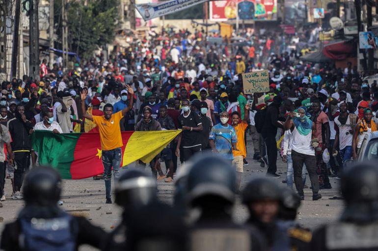 People protest in large numbers and display Cameroon flag.