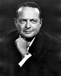 A person in a suit with his hand on his chin
Description automatically generated