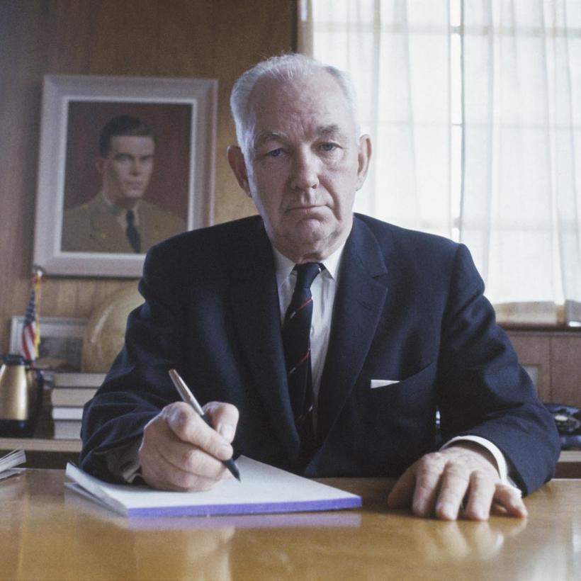 A person in a suit writing on a book

AI-generated content may be incorrect.