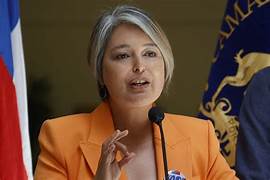 A person in an orange jacket speaking into a microphone

AI-generated content may be incorrect.