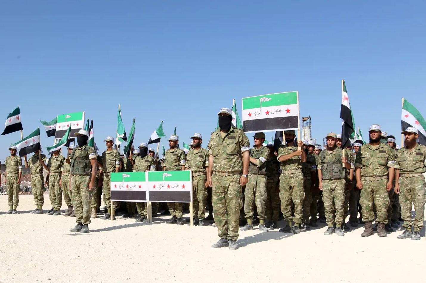Fighters from Jaish al-Izzah, part of the Free Syrian Army, stand in attention during a military display as part of a graduation ceremony at a camp in the Hama province, Syria July 29, 2016. REUTERS/Ammar Abdullah - RTSK90N