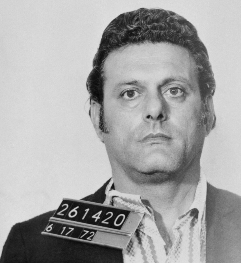 A person in a suit with a sign on his neck

AI-generated content may be incorrect.